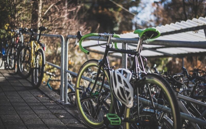 Rowery przypięte do barierki, na kierownicy kask rowerowy